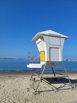 Lifeguard tower standing over quiet sand and calm Sail Bay water under clear blue morning sky in San Diego, California