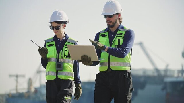 Marine engineers use a tablet to supervise cargo operations, container transport and logistics infrastructure at a commercial port, harbor, infrastructure, distribution, freight, commercial shipping.