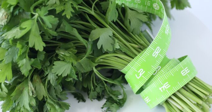Measuring tape and parsley on table, spinning. Closeup view