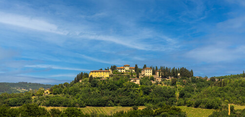 Obraz premium Scenic hilltop village in Tuscany, Italy. A Wide angle landscape shot of charming medieval italian village perched atop of rolling hill in the heart of the Tuscan countryside.