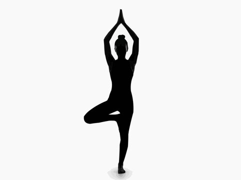 Silhouette of a woman in a yoga tree pose for the concept of balance and meditation.