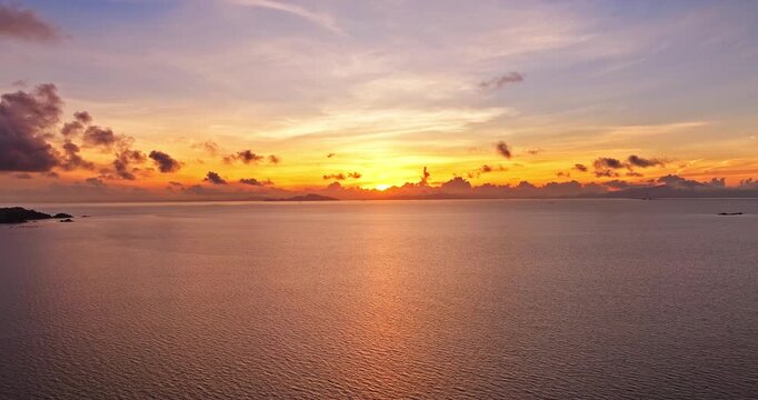Aerial view of a golden sunrise over the calm sea with clouds on the horizon, Zhuhai, China