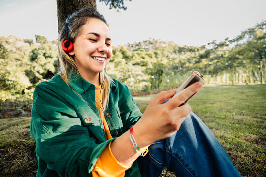 Happy woman listening music with vintage headphones and cassette radio player at park city - Nostalgia lifestyle trend