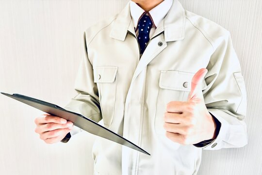 バインダーを持って親指を立てる作業着男性