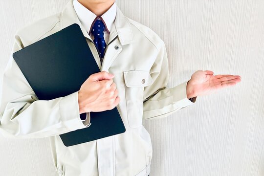 バインダーを持って紹介する作業着スタッフ
