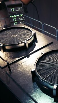 Two cooking surfaces are placed on a metal counter. The setup is part of a kitchen or food preparation area. The lights are bright, and the space appears organized.