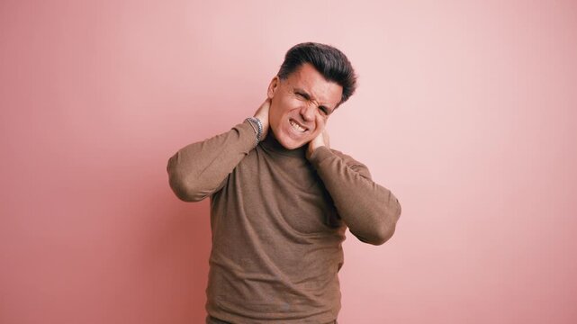 Unhappy mature man feeling pain in his neck and massaging it with his hands. Studio shot showing a person suffering from muscle injury