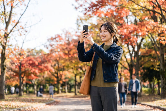 紅葉の公園でスマホ撮影する女性 Generative AI