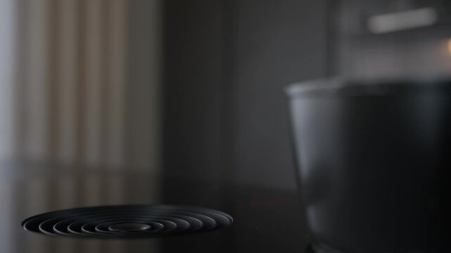 Close up of a sleek black induction hob featuring a builtin ventilation system. Ideal for content about modern home design, smart kitchen appliances, and minimalist interior styling.