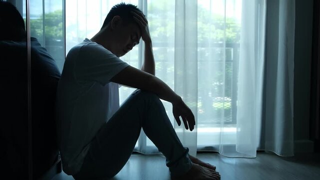 A young man sat in the corner of the room with his hands clasped. He was experiencing emotional and mental problems; he had depression and stress from social and work issues .medical concept