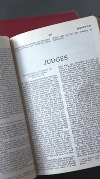 Kuala Lumpur, Malaysia - June 25th, 2026: Opening to the Book of Judges of the Old Testament in the Holy Bible. New Revised Standard Version. Vertical video.