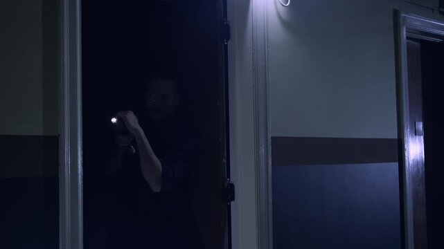 Police officer action shot searching an old warehouse with a flashlight
