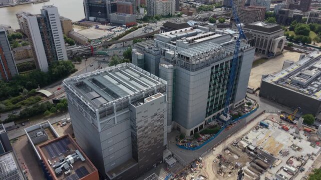 Drone flight above a large data center facility being built in London, United Kingdom. This daytime shot captures the extensive construction activity and modern urban landscape along the River Thames.