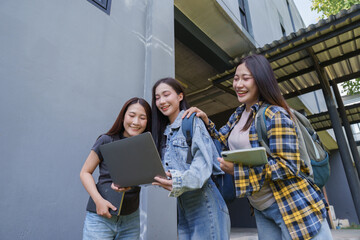 Fototapeta premium Female students collaborating on laptop studying on campus street