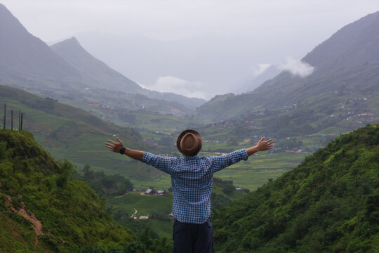 Male traveler raising arms enjoying Sapa mountain valley.