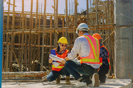 Structural engineer, architect and foreman worker with blueprints discuss, plan working for the outdoors building construction site. Construction collaboration concept