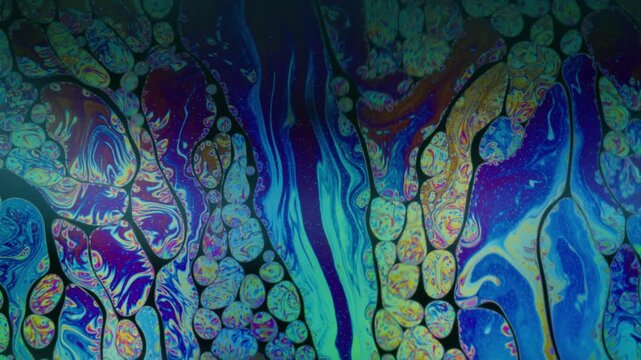 Iridescent fuel. Paint mix. Defocused blue yellow purple colorful round oil texture chemical drop liquid spill on abstract art background.