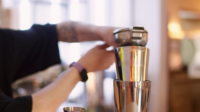 Fruit alcohol beverage. Bar service. Barkeeper hand squeezing fresh citrus juice with professional tool pouring aroma liquid in cocktail shaker.