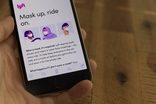 A hand holds a smartphone displaying a Lyft email that requires drivers and riders to wear face coverings for every ride during the COVID-19 pandemic.