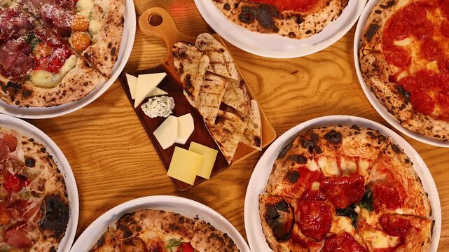 Overhead View of Neapolitan Pizzas and Italian Antipasto on Wooden Table