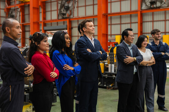 Diverse group of worker engineer and manager standing in factory showing confident emotion with crossed arm. Working team looking proud and focused in industrial warehouse environment together
