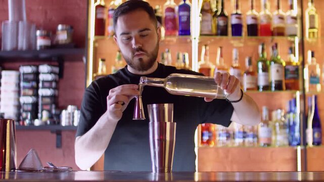 Pub drink preparing. Expert barman. Skillful bearded male bartender pouring alcohol beverage syrup using professional shaker at workplace.