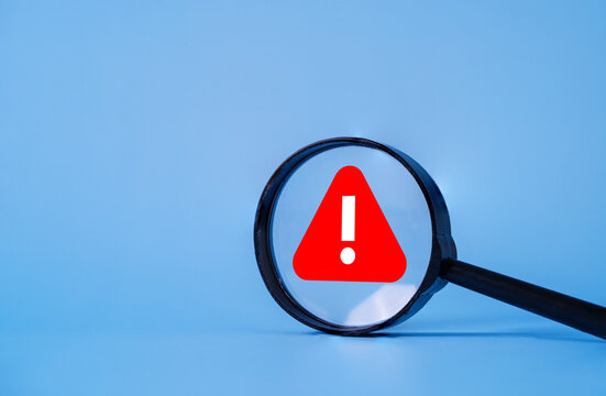 Magnifying glass highlighting a warning symbol represents risk assessment, business alert, cybersecurity threat, compliance monitoring, danger detection, problem analysis and security awareness.