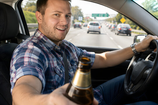 Smiling man offering a beer bottle while driving in highway traffic