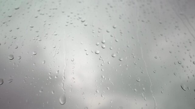 Close up Motion up Raindrops on Glass Window against bright overcast sky
