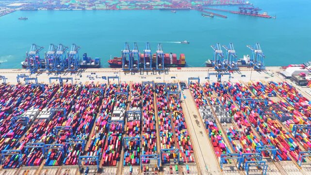 Aerial drone view of Qingdao fully automated smart container port, unmanned intelligent dock with automated cranes and container stacks for global shipping logistics。