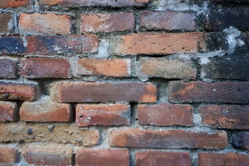 Fototapeta premium Weathered red brick wall with natural white efflorescence and aged texture, creating a rustic background for architectural and design projects.