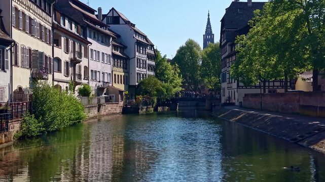 Quai de la Petite France follows the Ill River toward Pont du Faisan and Cath&eacute;drale Notre-Dame de Strasbourg in Strasbourg, Bas-Rhin, Grand Est, Alsace, France, slow low-altitude drone forward flight.