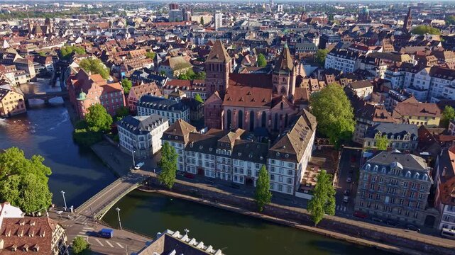 &Eacute;glise Saint-Thomas rises above Pont Saint-Thomas and the Ill River in Strasbourg, Bas-Rhin, Grand Est, Alsace, France, drone lateral slide left.