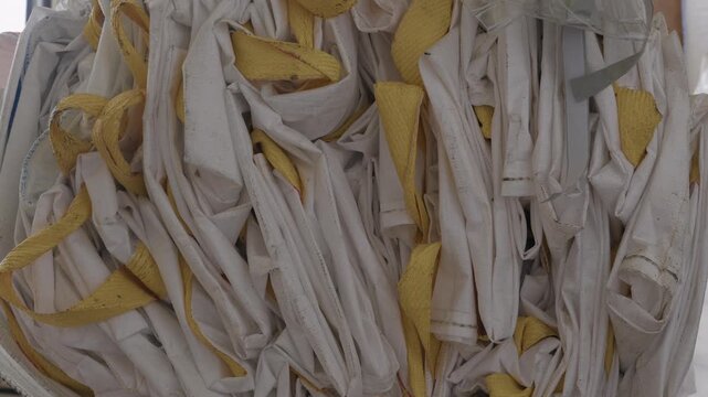 Pile Of Empty White And Yellow Woven Polypropylene Bulk Bags Awaiting Recycling