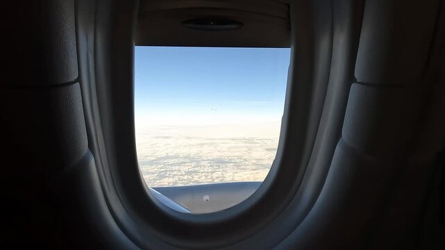 Close-up view of an airplane window with soft daylight and subtle exterior scenery, emphasizing the passenger cabin experience during flight.