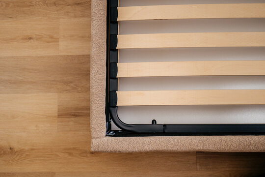New wooden slats are placed on the bed base in a bedroom for support and comfort