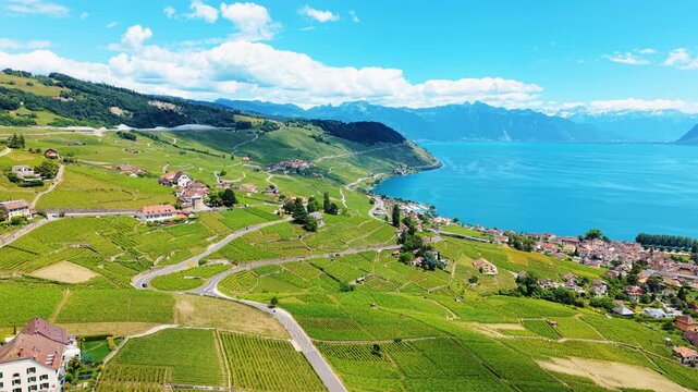 Aerial: pan drone shot of Cully cityscape, Lavaux terraced vineyards and Lake Geneva during the day in Cully, canton of Vaud, Switzerland