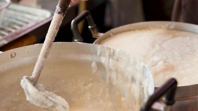 Close Up of Chef Stirring Rice Congee in Large Metal Pot