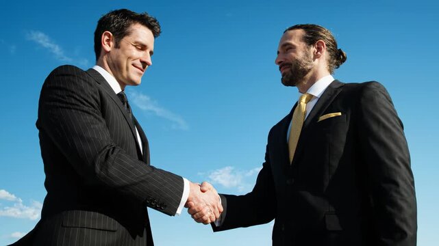 Two Businessmen Shaking Hands Outdoors Under Blue Sky