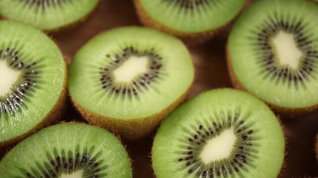 Close-up of fresh kiwi fruits arranged on a wooden table. Whole and sliced kiwis showing their vibrant green flesh and tiny black seeds under natural light. Ideal for themes of healthy eating, fresh f