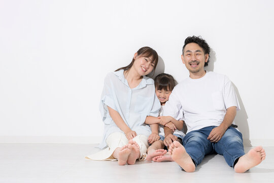 白背景で仲良し笑顔の家族・幸せなファミリーライフと健康的な暮らし　保険やnisaなど教育や成長　全身で座る半袖夏イメージに