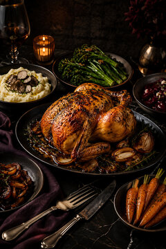 Candlelit roasted chicken with truffle mashed potatoes broccolini beets carrots onions rosemary and dark elegant table for gourmet holiday dining festive family meal