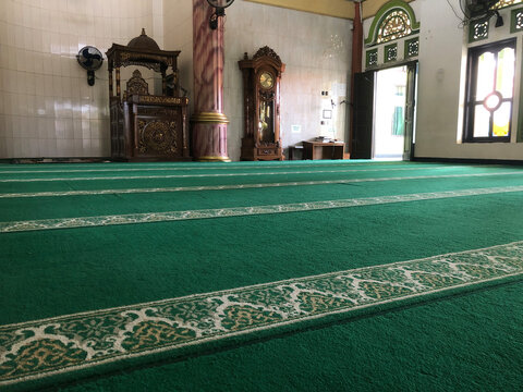 Modern mosque prayer room interior with elegant green carpet and wall ornament