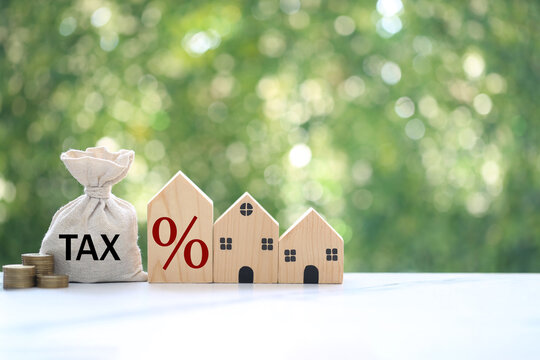 Wooden house models and a money bag with a tax percentage symbol, symbolizing real estate property tax, mortgage and financial planning.