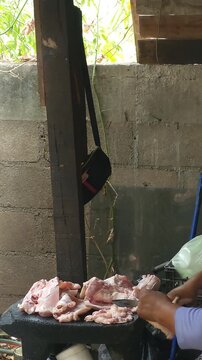 Woman cutting raw pork skin chunks on a table to prepare cracklings