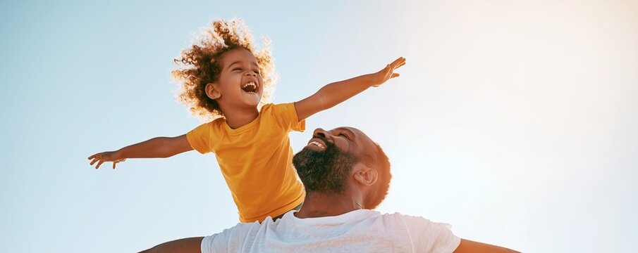 Happy African American father giving his joyful daughter a piggyback ride against a clear blue sky, concept for family bonding, lifestyle promotion and summer advertising