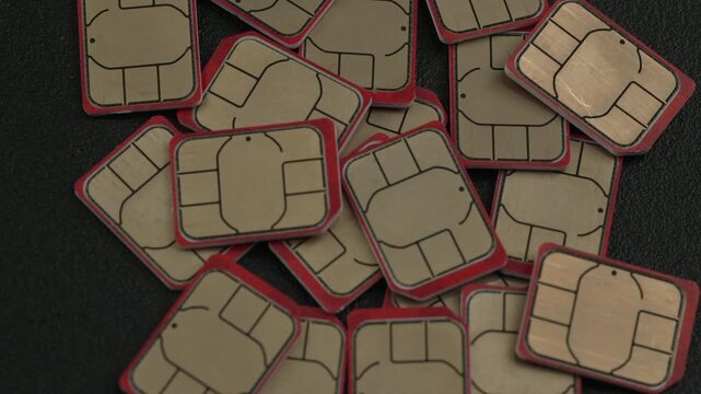 A collection of SIM cards with distinct red edges arranged on a textured black surface. Ideal for technology or telecommunications content.