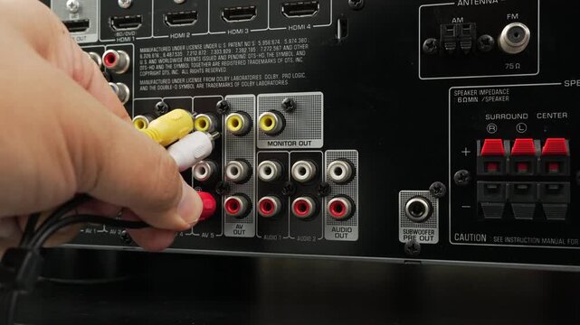 Male hand connects yellow and red RCA cables into the monitor out ports of an o video receiver, emphasizing analog connections and home entertainment setup.