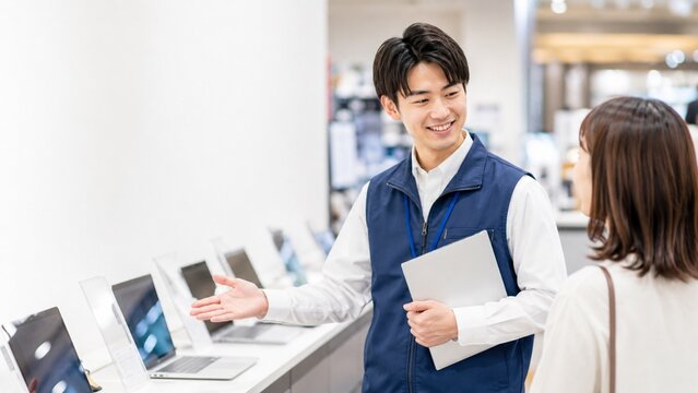 家電売り場でノートパソコンを案内する販売スタッフ