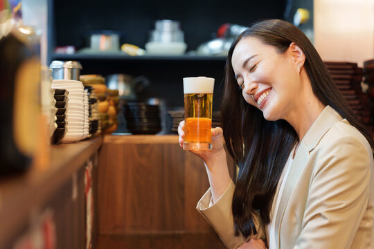 居酒屋で生ビールを飲むビジネスウーマン